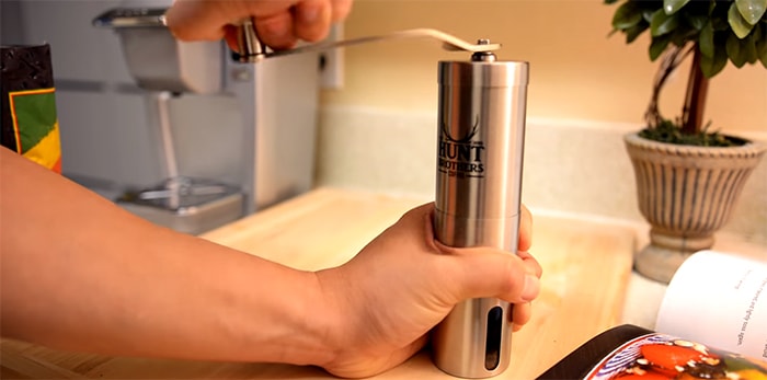 A manual burr coffee grinder being held by our reviewer.