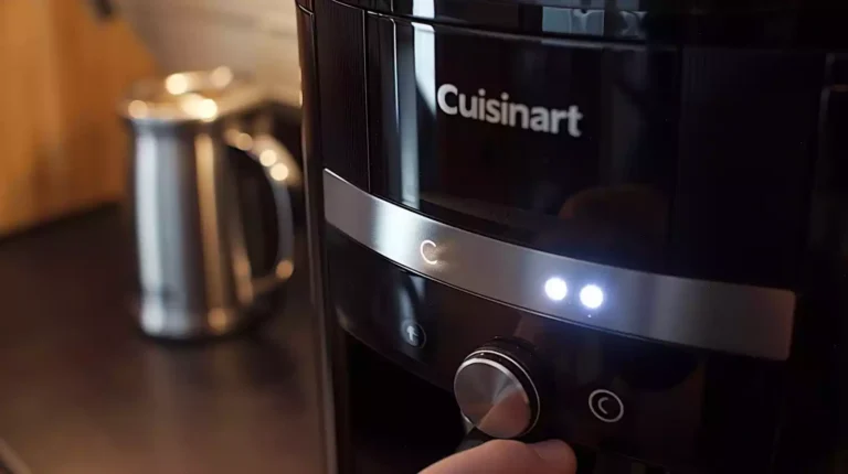 A hand pressing and holding the main button on a Cuisinart coffee maker while the light blinks. Include the coffee maker's sleek design and clear buttons.