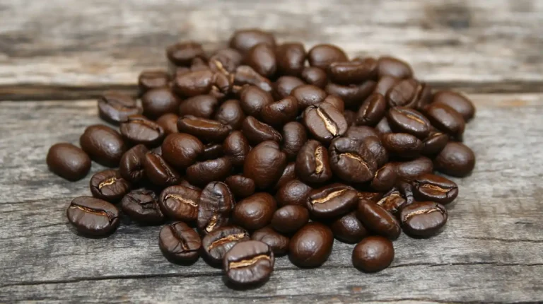 Close-up of freshly roasted coffee beans scattered on rustic wooden surface, showing rich chocolate-brown color, slight oily sheen, uniform coloring throughout, no scorching or pale spots.